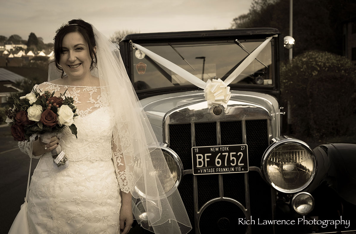 Bride standing by wedding car