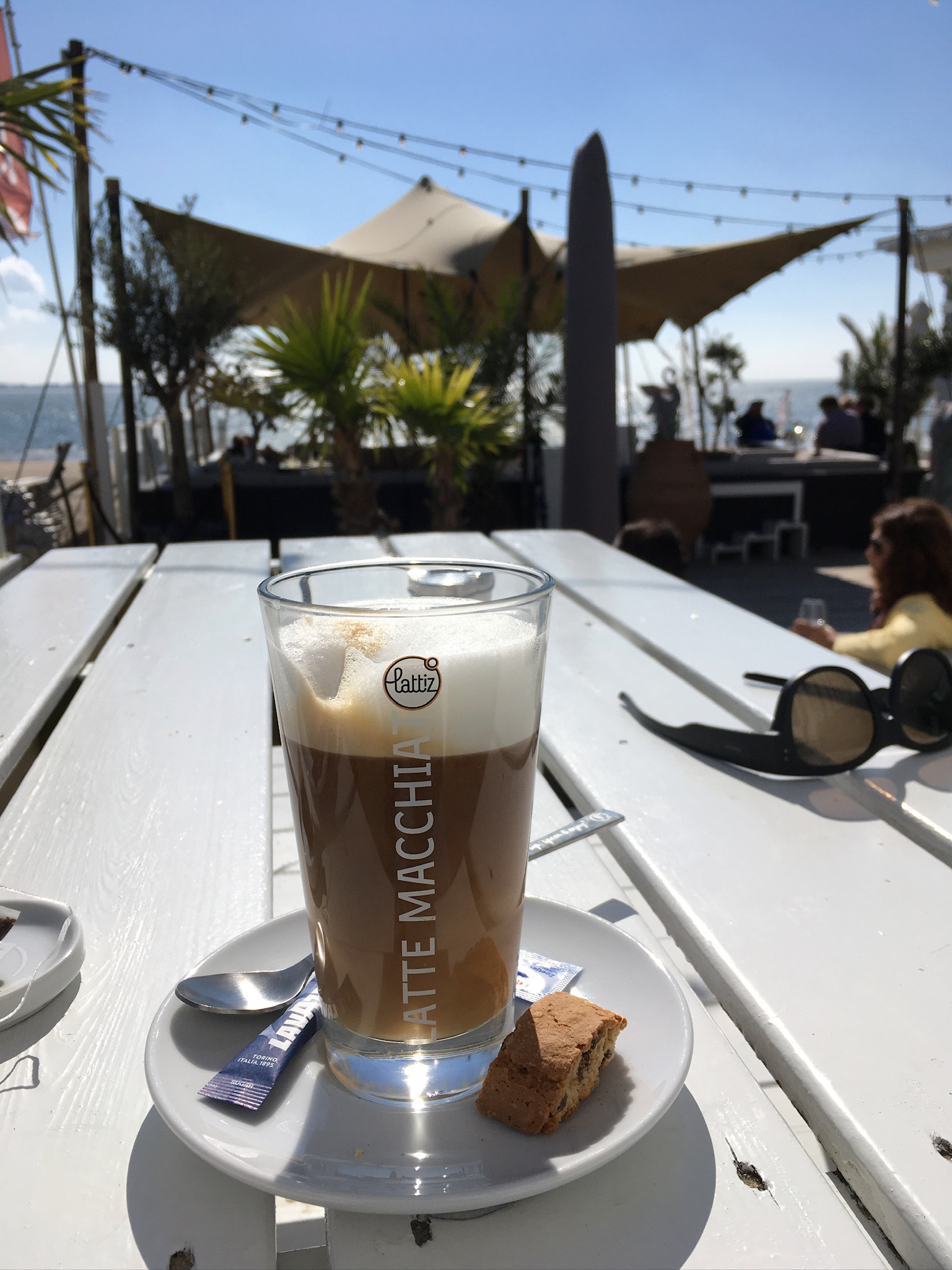 Latte Machiato auf einem Tisch am sonnigen Strand